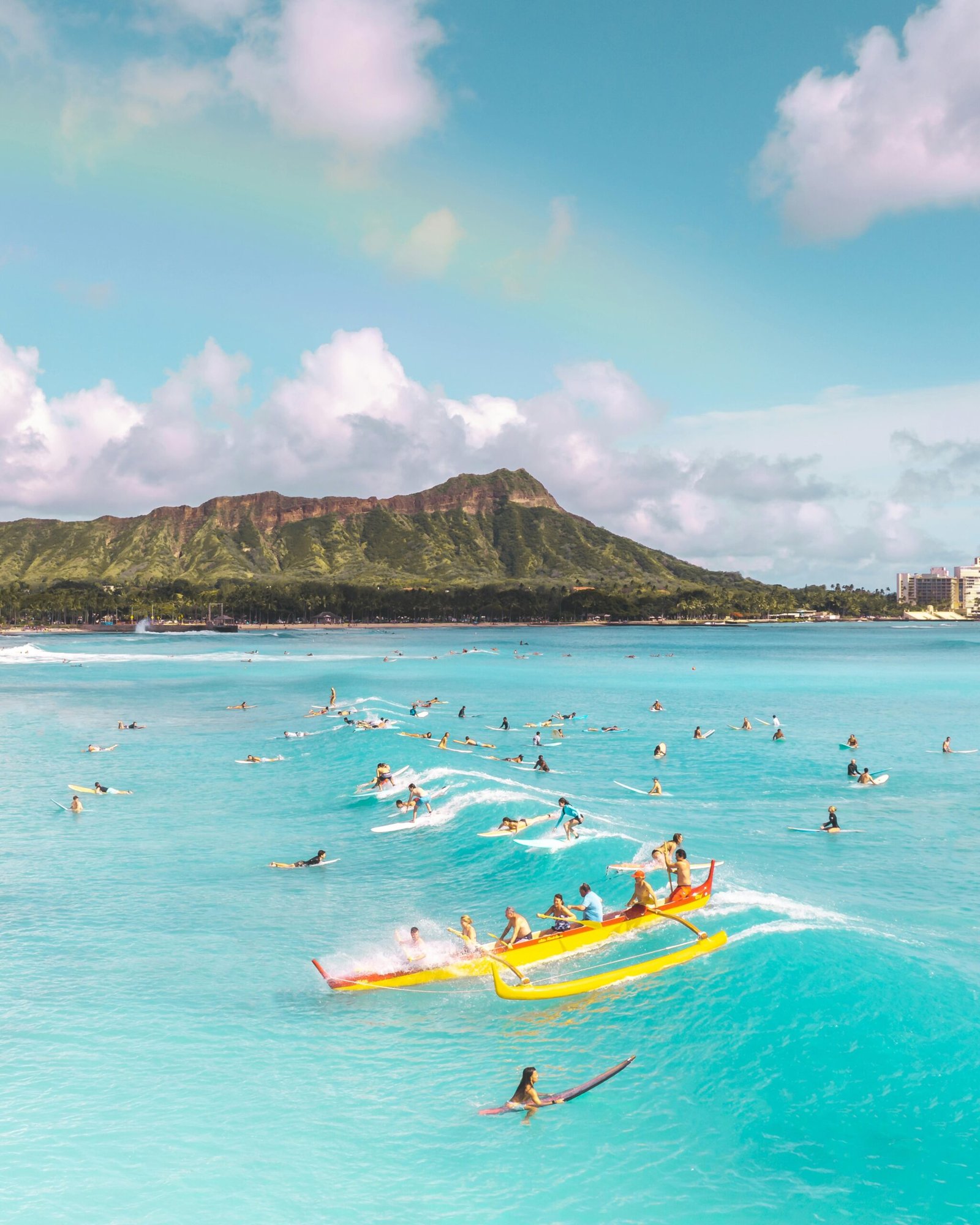 Stock photograph of surfers and canoe with Diamond Head in the background.